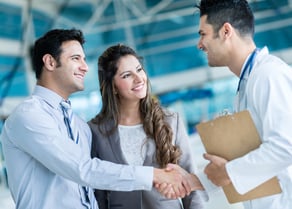Family doctor handshaking a couple at the hospital Family doctor handshaking a couple at the hospital